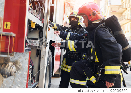 Group of firefighters in protective uniform that outdoors near truck 100539891