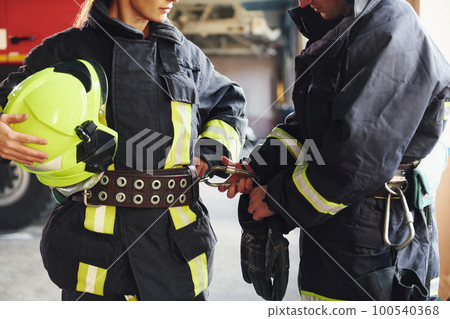 Male and female firefighters in protective uniform standing together Male and female firefighters in protective uniform standing together 100540368