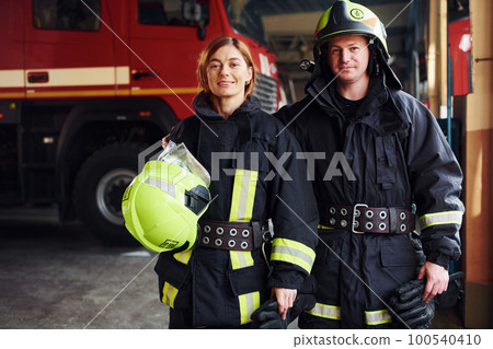 Male and female firefighters in protective uniform standing together 100540410