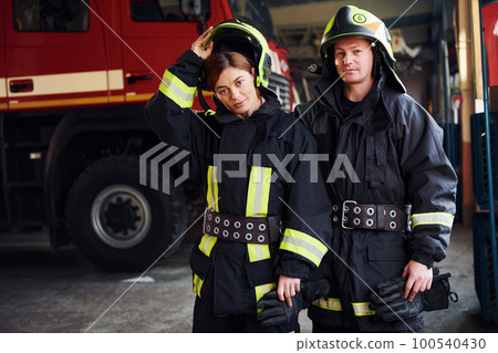 Male and female firefighters in protective uniform standing together 100540430