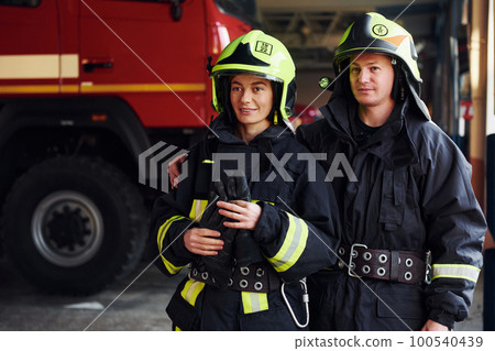 Male and female firefighters in protective uniform standing together 100540439