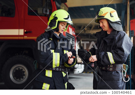 Male and female firefighters in protective uniform standing together 100540461