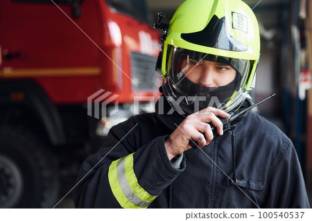 Male firefighter in protective uniform standing near truck 100540537