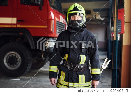 Male firefighter in protective uniform standing near truck Male firefighter in protective uniform standing near truck 100540545