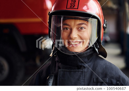 Close up view. Female firefighter in protective uniform standing near truck 100540687