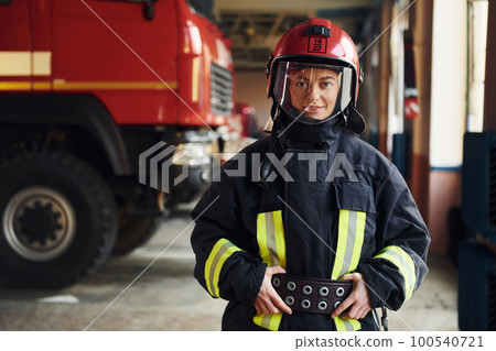 Female firefighter in protective uniform standing near truck 100540721