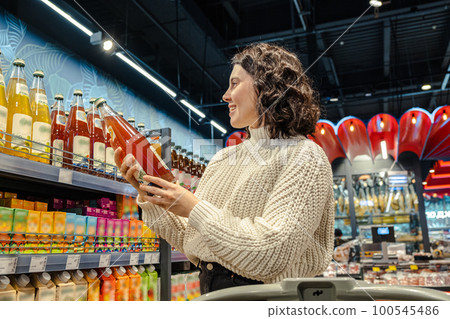 Woman picks juice in crowded grocery store 100545486