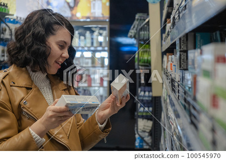 a woman chooses toothpaste in a store a woman chooses toothpaste in a store 100545970