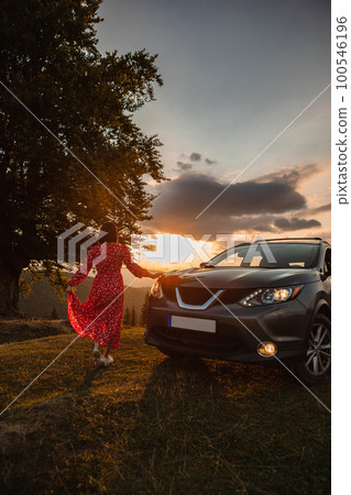 Woman near car. Sunset in the mountains 100546196