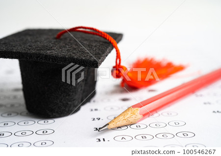 Graduation gap hat and pencil on answer sheet background, Education study testing learning teach concept. 100546267