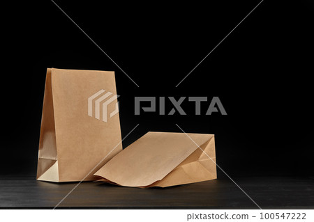 Eco friendly disposable tableware standing on dark surface against black background. Biodegradable craft dishes. Recycling concept. Close-up shot. 100547222