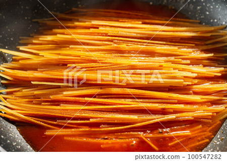 Making assassin's pasta, adding tomato stock 100547282