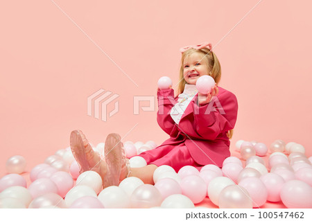 Photo of little girl with blond hair wearing pink clothes and sunglasses, playing with balls with hands over pink background. Concept of emotions, childhood, children's games, ad Photo of little girl with blond hair wearing pink clothes and sunglasses, playing with balls with hands over pink background. Concept of emotions, childhood, children's games, ad 100547462