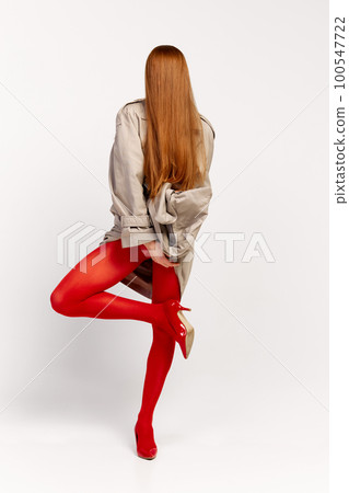 Impersonal human emotions. Stylish girl in grey coat and bright red tights moves over light background. Expressive fashion. Concept of art photography, beauty 100547722