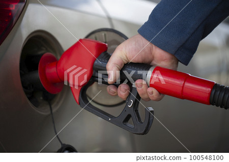 A hand holds a pistol for refueling with gasoline. A hand holds a pistol for refueling with gasoline. 100548100