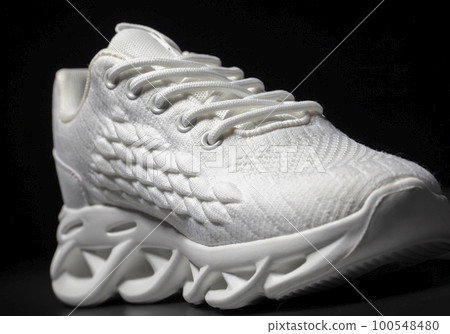 White fabric sneaker with embossed sole on a black background. White fabric sneaker with embossed sole on a black background. 100548480