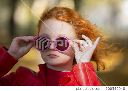 Portrait of a stylish red-haired girl in purple round sunglasses. Portrait of a stylish red-haired girl in purple round sunglasses. 100549048