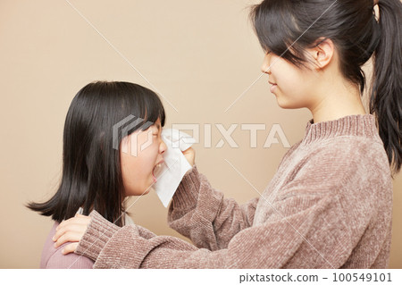 A sister wiping her crying sister's tears 100549101