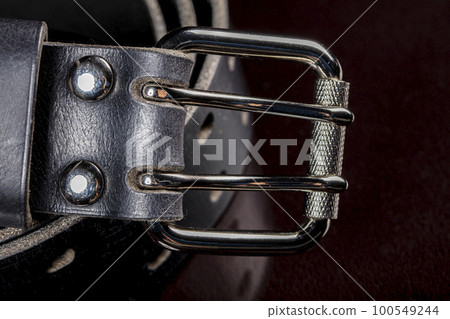Black leather belt on a dark background. Leather products. Black leather belt on a dark background. Leather products. 100549244
