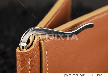 Part of a brown leather wallet or case with stitching. 100549253