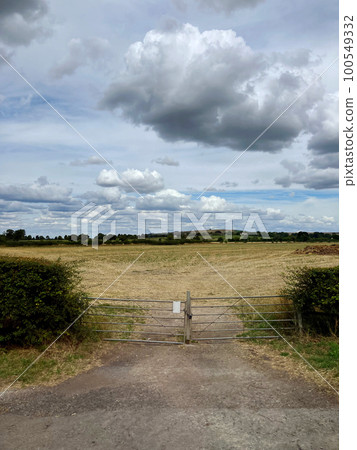 Clouds floating in the air, the prairie spreading behind the closed gate and rolling hills Clouds floating in the air, the prairie spreading behind the closed gate and rolling hills 100549332