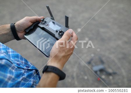 Man holds remote control in hands and controls drone 100550281