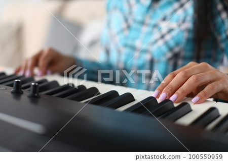 Woman hands playing electric piano at home performing musical composition closeup 100550959