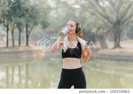 After a workout, a fatigued woman is taking a break to rest. During this time, she is contemplating her goals, progress, and performance as an athlete. 100550962