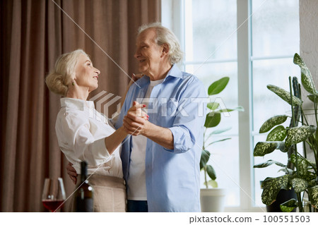 Happy beautiful mature, senior couple, retired man and woman spending lovely time together at home, dancing, having dinner, drinking wine Happy beautiful mature, senior couple, retired man and woman spending lovely time together at home, dancing, having dinner, drinking wine 100551503