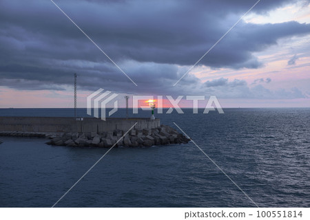 Sunrise from green lighthouse on maritime breakwater 100551814