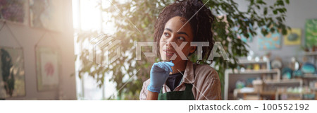 Woman florist takes care of seedlings in floral studio. Gardening concept. Blurred background Woman florist takes care of seedlings in floral studio. Gardening concept. Blurred background 100552192