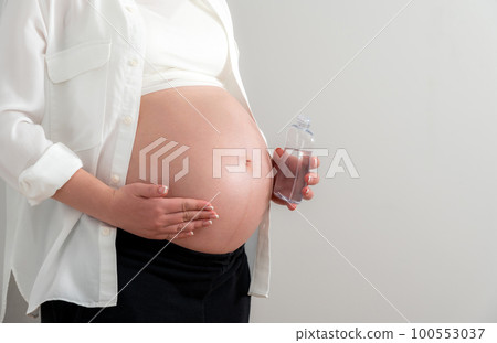 Pregnant woman applying cosmetic oil on her belly for healing stretch marks and skin elasticity 100553037