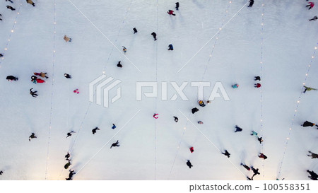 Many people skating on beautiful ice skating rink in open air decorated New Year Christmas illuminations, decorations, luminous garlands on winter night. New Year Christmas holiday celebration. Aerial 100558351