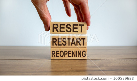 Male hand placing a block with word 'reset' on top of a blocks tower on wooden table. Beautiful white background. Male hand placing a block with word 'reset' on top of a blocks tower on wooden table. Beautiful white background. 100559688