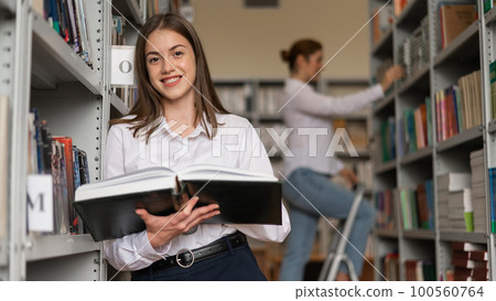 Two young female students in a public library. Two young female students in a public library. 100560764