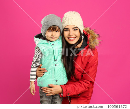 Happy mother and son in warm clothes on pink background. Winter vacation 100561872