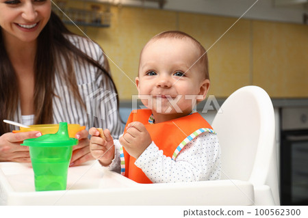 Young mother feeding her little baby at home Young mother feeding her little baby at home 100562300