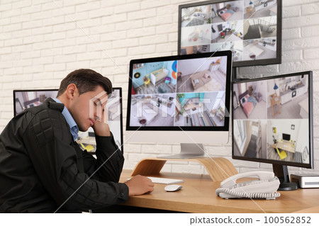 Male security guard sleeping near monitors at workplace 100562852