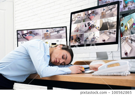 Female security guard sleeping near monitors at workplace 100562865