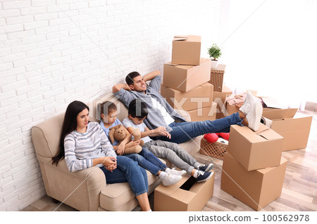 Happy family resting in room with cardboard boxes on moving day Happy family resting in room with cardboard boxes on moving day 100562978