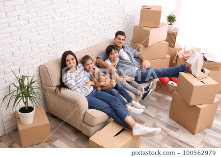 Happy family resting in room with cardboard boxes on moving day Happy family resting in room with cardboard boxes on moving day 100562979