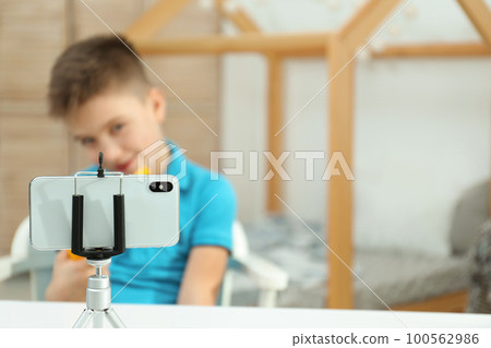 Cute little blogger with toy recording video at home, focus on phone Cute little blogger with toy recording video at home, focus on phone 100562986