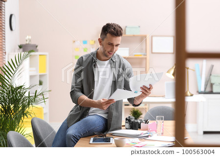Journalist with papers at workplace in office 100563004