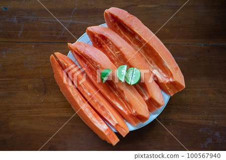 Sliced papaya with lime on table near swimming pool Sliced papaya with lime on table near swimming pool 100567940