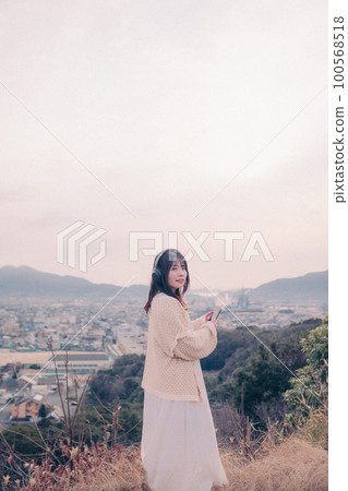照片中一位女士在早晨的陽光下以城市為背景聽音樂 100568518