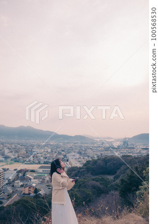 照片中一位女士在早晨的陽光下以城市為背景聽音樂 100568530