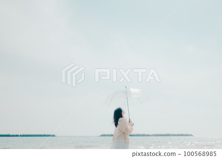 Photo of a woman holding an umbrella on the beach 100568985