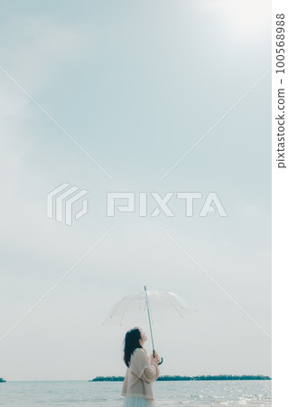 Photo of a woman holding an umbrella on the beach 100568988