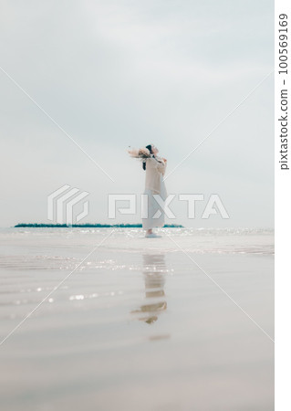 Photo of a woman holding dried flowers on the beach Photo of a woman holding dried flowers on the beach 100569169