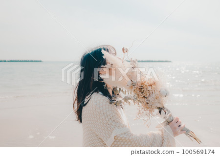 海邊拿著乾花的女人照片 100569174